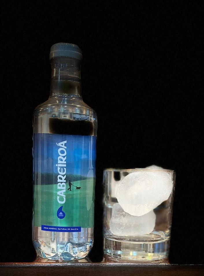 Botella de agua mineral con iluminación suave sobre fondo oscuro.