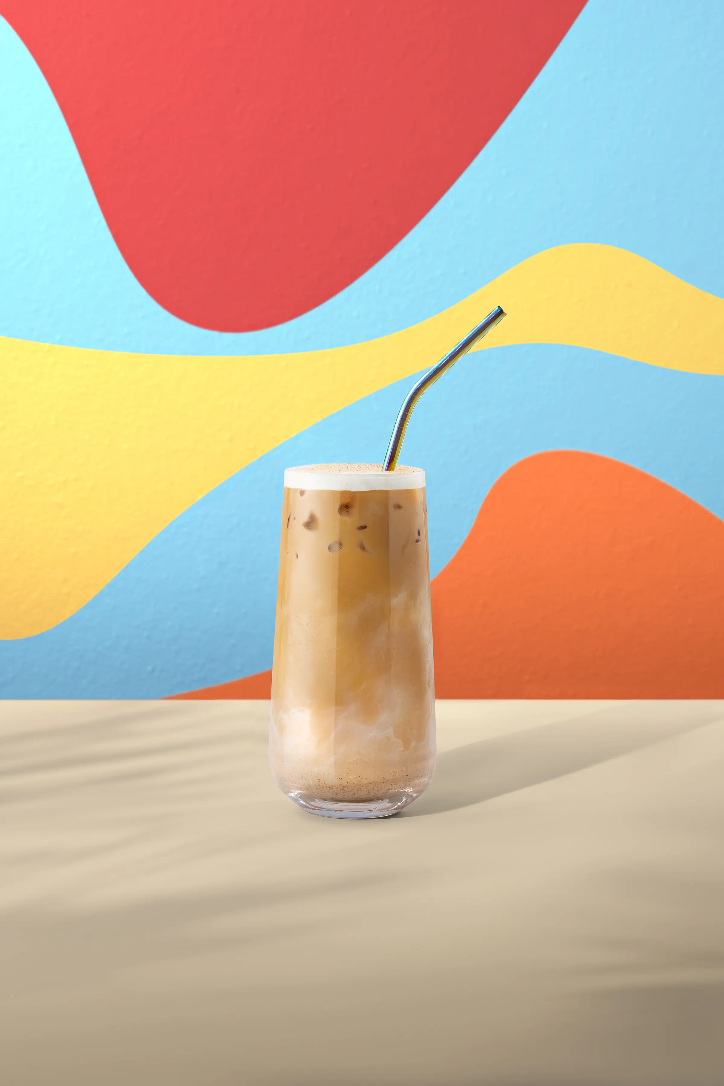 Chai latte frío servido en vaso alto, con mezcla cremosa y fondo colorido.