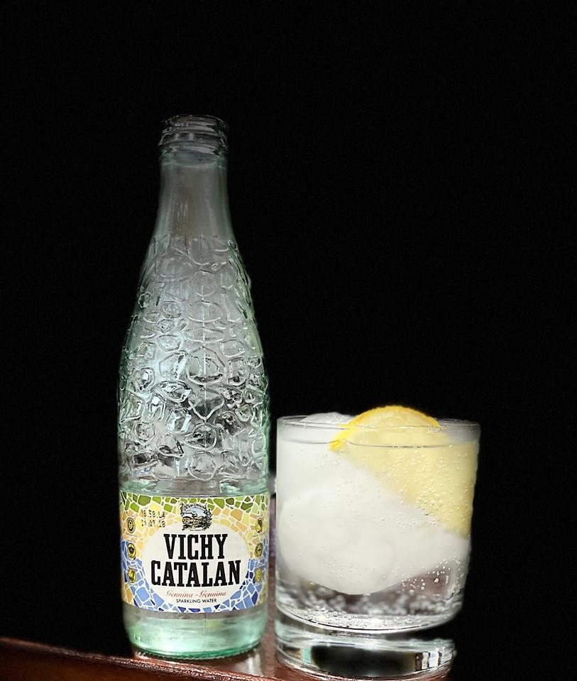 Botella de agua Vichy Catalán sobre fondo oscuro con iluminación suave.